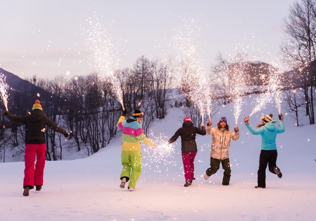 Snow borders holding sparklers in the snow to celebrate New Year's in Aspen