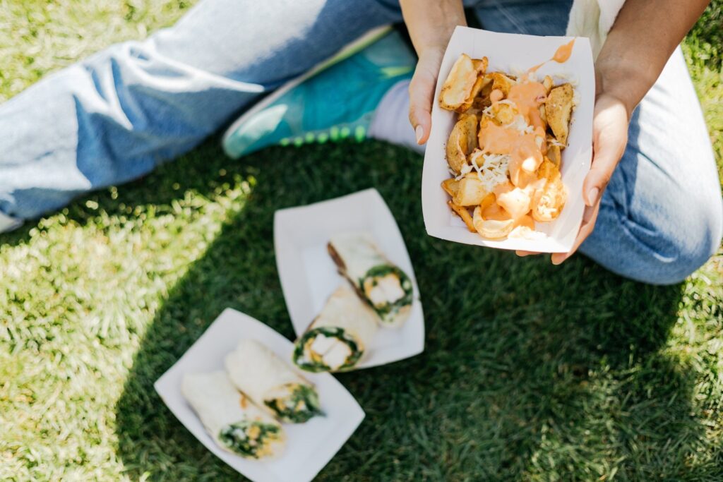 A person holding a plate of food on the grass at the Taste of Vail event.