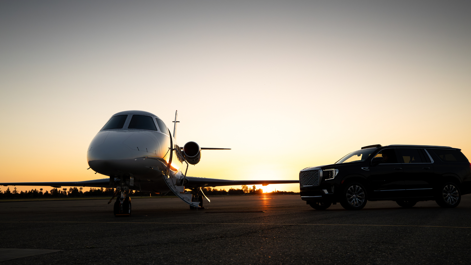 A luxury private transfer service waiting on a tarmac at sunset, with the sun low on the horizon.